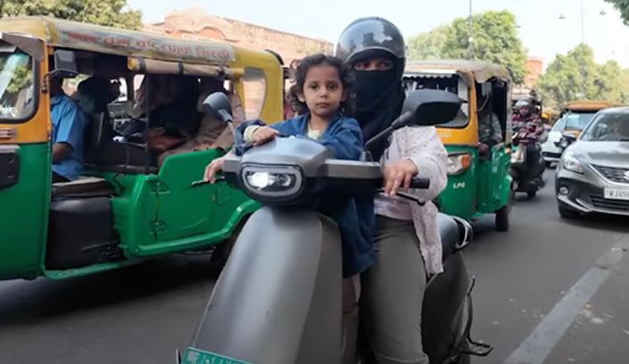 A child without a rash helmet rides at the front of a motorcycle in Jaipur.